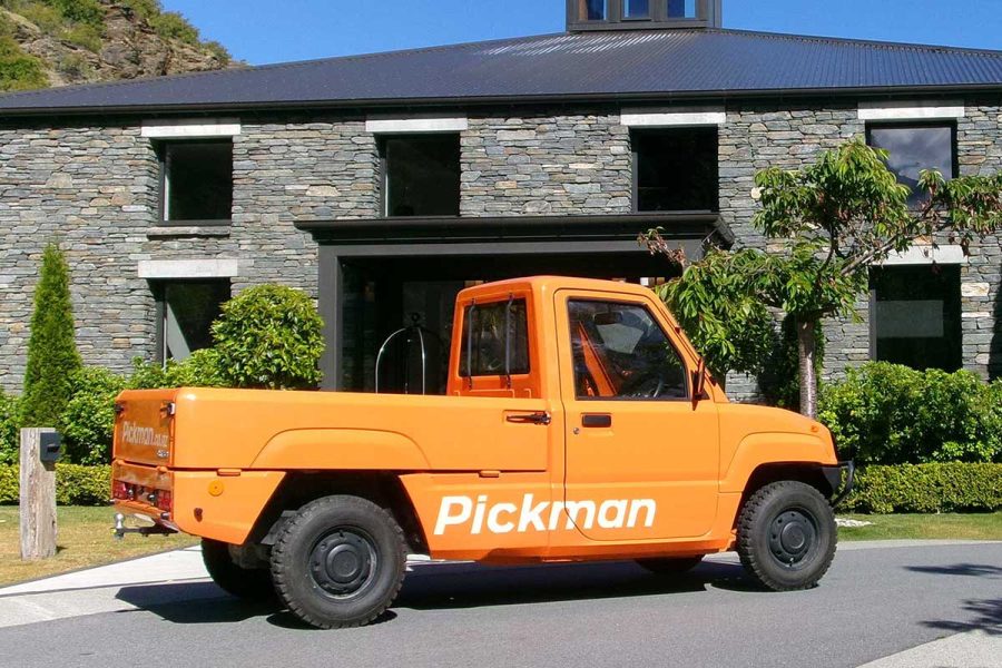 ornage pickman electric vehicle in new zealand outside a stone luxury lodge